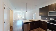 Located at Flint Street in Lenexa, Kansas, this single-floor unit showcases a contemporary design with a thoughtful open-concept layout. The kitchen serves as a central highlight, featuring dark espresso cabinetry that extends to the ceiling, quartz countertops with subtle veining, and a large island with an undermount sink and pendant lighting overhead. Stainless steel appliances, including a side-by-side refrigerator with ice maker, electric range, built-in microwave, and dishwasher, complete the well-appointed space. The kitchen flows seamlessly into the living area, which is finished with wood-look flooring and a ceiling fan, while large windows invite natural light throughout.

The bedrooms are carpeted for comfort and feature ceiling fans, generous windows, and sliding glass doors leading to private balconies with views of the surrounding community. The primary bathroom is appointed with a dual-sink quartz vanity, dark cabinetry, wood-look flooring, and a tiled walk-in shower with a glass sliding door. A secondary bathroom mirrors the same refined aesthetic, offering a quartz vanity and a tiled tub-shower combination, rounding out a cohesive and modern interior.