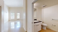 This single-floor unit in Oakland, CA offers a clean, modern aesthetic defined by striking soaring ceilings that lend an expansive, airy feel throughout. Polished concrete floors run seamlessly across the main living areas, reflecting natural light and enhancing the sense of openness. Large windows frame views of surrounding greenery, flooding the living space with abundant daylight.

The kitchen is well-appointed with crisp white cabinetry, dark countertops, and a full suite of stainless steel appliances, including a gas range, built-in microwave, dishwasher, and refrigerator. Recessed lighting and ample cabinet storage make this an efficient and attractive workspace.

The living area is generously proportioned, with soaring walls and an open layout that connects fluidly to the rest of the unit. The bedroom features warm-toned flooring, tall ceilings, and a sliding-door closet with built-in hanging rods and shelving, providing practical storage. A second closet space is also present, similarly outfitted with dual hanging rods.

The bathroom includes a vanity with dark countertops, white cabinetry, a toilet, and a full bathtub with shower and built-in shelving. Throughout the unit, the neutral white palette, clean lines, and thoughtful layout create a calm, functional living environment well-suited to the vibrant Oakland, CA location.