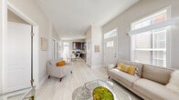 Located at 8250 Lankershim Blvd in Los Angeles, CA, this thoughtfully designed 2-bedroom, 2-bathroom residence offers a bright and modern living experience across a single floor. The open layout connects a welcoming living room to the kitchen and dining area, creating a cohesive flow throughout the space. The living room stands out with soaring ceilings, oversized windows with transom panels that flood the area with natural light, and light wood-look tile flooring that extends seamlessly throughout the home. A kitchen anchors the back of the unit, featuring rich dark espresso cabinetry with glass-front upper panels, white quartz countertops, stainless steel appliances including a refrigerator and built-in microwave, and a bright window above the sink. A compact dining area sits adjacent to the kitchen. Both bedrooms are well-proportioned and naturally lit, with multiple windows framing neighborhood views, neutral wall tones, and the same light-toned tile flooring. The two bathrooms are clean and functional — one features a full tub-shower combination with white tile surround, while the other offers a pedestal sink and medicine cabinet. Throughout, the neutral color palette, recessed lighting, and consistent finishes create a cohesive, modern ambiance well-suited for comfortable urban living.