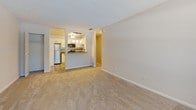 Located at 2738 Roosevelt Blvd in Largo, Florida, this single-floor unit offers a thoughtfully designed layout with clean, neutral finishes throughout. The living area is spacious and inviting, featuring plush wall-to-wall carpeting, neutral-toned walls, and a textured ceiling that adds subtle character. A front entry door with an adjacent window allows natural light to filter into the space, creating a bright and welcoming atmosphere.

The kitchen is a standout feature, boasting white shaker-style cabinetry, granite countertops, a tile backsplash, and a full suite of stainless steel appliances including a refrigerator, range, and over-the-range microwave. Warm pendant lighting and light wood-style flooring complete the kitchen's modern appeal. A pass-through opening connects the kitchen to the living area, enhancing the open feel of the floor plan.

The bedrooms are generously sized, each finished with soft carpeting and window blinds that provide natural light while maintaining privacy. The bathroom is well-appointed with a white shaker vanity, granite countertop, a framed mirror, wood-look flooring, and a full tub-shower combo with clean white tile surround. The overall ambiance is bright, move-in ready, and well-maintained.