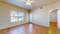 This single-story space is finished with warm-toned hardwood-style flooring that runs consistently throughout every room, creating a cohesive and easy-to-maintain interior. The living area is generously sized, featuring a ceiling fan with integrated lighting, a large window fitted with horizontal blinds that invites natural light, and a glass-panel entry door providing direct outdoor access and additional brightness. A partial wall with a breakfast bar separates the living space from the kitchen, maintaining an open feel while defining each functional zone.

The galley-style kitchen is lined on both sides with light wood cabinetry offering ample upper and lower storage. It is equipped with a white refrigerator, dishwasher, double-basin sink, and an electric range. A central electrical panel is also accessible from within the kitchen.

The bedroom is a comfortable size, featuring a ceiling fan, a window with natural views, and direct access to a spacious walk-in closet outfitted with multi-tiered wire shelving systems along two walls, providing generous organization capacity.

The bathroom includes a wood-toned vanity with overhead cabinetry, a white countertop, toilet, and a full bathtub, all finished with the same consistent hardwood-style flooring found throughout the space.