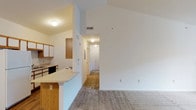 Located at Autumn Creek Court in Manchester, Missouri, this single-floor unit offers a well-organized layout with a notably open feel enhanced by vaulted ceilings throughout the living areas. The living room is generously proportioned, featuring neutral carpet, a ceiling fan, and a sliding glass door that admits natural light and provides outdoor access. A defined entryway with hardwood-style flooring transitions smoothly into the main living space.

The kitchen is efficiently arranged with warm oak-toned cabinetry, white appliances including a full-size refrigerator and electric range, a built-in microwave, and a dishwasher. A peninsula with a breakfast bar counter separates the kitchen from the living area, creating an open, connected feel while maintaining functional workspace.

A hallway connects the living area to the private rooms, including a primary bedroom with vaulted ceilings, plush carpet, and a sliding-door closet. An additional bedroom features carpet and a window with views of surrounding greenery. The bathroom includes a single-sink vanity with wood-trimmed cabinetry, a large mirror, and a separate tub/shower combination with tile flooring, completing the functional layout of this well-maintained unit.