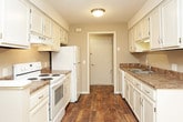 This single-floor residence offers a practical and comfortable layout designed for everyday living. The kitchen serves as a functional hub, featuring white cabinetry, granite-style countertops, a stainless steel sink, and white appliances including a range and refrigerator. Warm wood-look flooring runs throughout the kitchen and flows toward the adjacent dining area, which is accented by a chandelier overhead.

The bedrooms are generously proportioned, each finished with soft, neutral-toned carpeting and ceiling fans with integrated lighting. Multiple bedrooms feature sliding closet doors for convenient storage, while large windows dressed with vertical blinds allow natural light to fill the rooms, creating a bright and airy atmosphere. Clean white trim and muted taupe walls maintain a cohesive, understated aesthetic throughout.

The bathrooms are neatly appointed with tile flooring, a full tub and shower combination with classic subway-style tile surround, a toilet, and a vanity topped with granite-style counters and white cabinetry beneath. A large mirror above the vanity adds depth to the space.

Overall, the residence presents a clean, move-in-ready environment with consistent finishes, ample storage, and a straightforward floor plan that maximizes functionality across all areas.