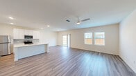 Located at 2601 Crystal Bend Drive in Pflugerville, Texas, this two-story home offers a well-designed layout spread across two floors. The main level features an open-concept kitchen and living area with stylish wood-look flooring, recessed lighting, and a ceiling fan that enhances the bright, airy atmosphere. Large windows and a sliding glass door invite abundant natural light and provide views of the outdoors. The kitchen is outfitted with crisp white shaker cabinets, a tile backsplash, stainless steel appliances including a refrigerator, range, and microwave, and a central island with an undermount sink and light countertops — ideal for both cooking and casual dining. An attached garage with an automatic opener provides convenient interior access. Upstairs, the more expansive floor houses all four bedrooms, including a generously sized primary suite, along with two full bathrooms. The bedrooms are finished with plush carpeting and ample closet space, including walk-in closets with built-in shelving. The bathrooms feature tub-shower combinations with clean, white surrounds and wood-look flooring. A dedicated laundry area on the upper level includes a full-size side-by-side washer and dryer. The home's clean, neutral palette throughout creates a versatile and move-in-ready environment.