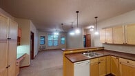 Located at 1310 Broadway Dr N in Fargo, North Dakota, this single-floor unit offers a practical and well-organized layout designed for comfortable everyday living. The open-concept kitchen flows seamlessly into the living area, creating a connected, spacious feel. The kitchen is outfitted with light maple cabinetry offering generous storage, dark laminate countertops, a double-basin sink, a dishwasher, electric range with overhead microwave, and a full-size refrigerator. Pendant lighting above the kitchen island adds a warm, functional touch. The adjoining living area features soft carpeting and multiple windows with blinds that allow natural light to filter through. The bedrooms are carpeted and well-proportioned, each featuring windows with outdoor views and baseboard heating. One bedroom includes a wall-mounted AC unit for added climate control. The unit includes two bathrooms: one with a full tub-shower combination and tile flooring, and another with a vanity, large mirror with bar lighting, and tile floors. A dedicated laundry area houses a full-size washer and dryer with overhead wire shelving. Warm wood-toned trim throughout ties the interior together, creating a cohesive and functional living environment.
