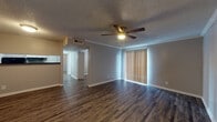 This single-floor residence offers a practical and well-organized layout across several distinct living areas. The living room serves as the central gathering space, featuring rich dark hardwood-style flooring, crown molding, a textured ceiling, and a ceiling fan with integrated lighting. Vertical blinds on a large window allow for adjustable natural light, and an open sightline connects the space to the rest of the unit.

The kitchen is efficiently designed with a galley-style layout, showcasing white cabinetry, dark granite-style countertops, a stainless steel sink, and black appliances including a refrigerator and electric range. Light wood-tone flooring complements the clean, crisp cabinetry.

The bedrooms are carpeted for comfort, each equipped with a ceiling fan and ample natural light from windows fitted with horizontal blinds. One bedroom features a built-in cabinet nook, offering additional storage. Closet access is also visible in the bedroom areas.

The bathroom presents a clean, minimalist design with a full tub-shower combination featuring white tile surround, alongside standard fixtures in a neutral palette.

Throughout the space, a consistent cool gray wall color, textured ceilings, and durable flooring choices create a cohesive and low-maintenance living environment.
