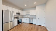 Located at 8749 Waterton Rd in Littleton, Colorado, this thoughtfully designed single-story unit offers a clean, modern aesthetic throughout its well-utilized floor plan. The open-concept living area features warm wood-look luxury vinyl plank flooring, neutral paint tones, and recessed lighting, creating a bright and welcoming atmosphere. The contemporary kitchen is a standout, outfitted with crisp white shaker cabinetry, granite-look countertops, and a full suite of stainless steel appliances including a French door refrigerator, electric range, built-in microwave, and dishwasher — all set atop matching LVP flooring that extends seamlessly from the living area. The generously sized bedroom features plush carpeting, a ceiling fan, and a window with natural light. Three closets provide ample storage, including a walk-in closet with wire shelving. The full bathroom is finished with a white vanity, granite countertop, a tiled tub-shower combination, and wood-look flooring for a cohesive look. Additional conveniences include in-unit laundry and a utility room. The space maintains a fresh, move-in ready feel with consistent modern finishes from room to room.