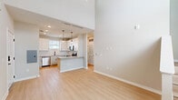 Located at 1302 Arena Boulevard in Clermont, Florida, this two-story, two-bedroom, two-bathroom home offers a well-designed layout spread across two floors. The main floor hosts the primary living areas, including an open-concept kitchen and living room, while the upper floor provides additional space.

The kitchen is a standout feature, outfitted with crisp white shaker cabinets, light quartz countertops, a hexagonal tile backsplash, and a full suite of stainless steel appliances including a side-by-side refrigerator, dishwasher, and gas range with over-the-range microwave. Light wood-look flooring flows throughout, complementing the neutral, airy palette.

The living room benefits from soaring double-height ceilings and oversized windows that flood the space with natural light, alongside access to a screened balcony offering open outdoor views. A staircase with white railings connects the floors.

The primary bedroom features a dedicated closet and connects to a well-appointed bathroom with a glass-enclosed walk-in shower, white subway tile, a single vanity, and matte black fixtures. The second bathroom includes a tiled tub-shower combination and matching vanity. Both bathrooms carry the same modern, clean aesthetic with light wood flooring and matte black hardware accents throughout.