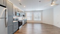Located at 2223 Lee Rd in Cleveland Heights, Ohio, this thoughtfully designed single-floor unit offers a clean, modern aesthetic throughout. The open-concept layout seamlessly connects the kitchen and living area, maximizing the efficient use of space while maintaining an airy, comfortable atmosphere.

The kitchen is a standout feature, outfitted with gray shaker-style cabinetry accented by matte black hardware, white quartz countertops, and a classic subway tile backsplash. A full suite of stainless steel appliances — including a refrigerator, electric range, over-the-range microwave, and dishwasher — provides everything needed for everyday cooking. The kitchen flows directly into the open living area, which is bathed in natural light through multiple large windows with blinds and finished with warm wood-look plank flooring. A ceiling fan adds both function and a finishing touch to the living space.

An entry hallway with two large paneled doors — ideal for closet storage — leads into the main living area, providing a practical and welcoming transition into the unit. The bathroom continues the cohesive design language with matching gray cabinetry, a white countertop vanity, a large mirror, and wood-look tile flooring, all set against crisp white walls for a clean, polished finish.