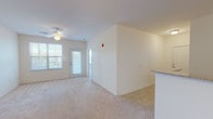 This single-floor residence offers three bedrooms and two bathrooms within a thoughtfully arranged layout. The living area is carpeted in neutral tones and benefits from natural light provided by a large window and a glass-paneled exterior door, which also offers access to an outdoor area. A ceiling fan with a light fixture provides additional comfort and illumination. Adjacent to the living space, the kitchen features warm-toned wood cabinetry, granite-style countertops, tile flooring, and black appliances including a range, microwave, and dishwasher, along with a double-basin sink.

Each of the three bedrooms is finished with plush carpeting and ceiling fan light fixtures. Two of the bedrooms feature windows with blinds that allow natural light and outdoor views, while all bedrooms include closet space. The primary bedroom is notably spacious with direct access to its own bathroom area.

The two bathrooms are finished with tile flooring. One features a double-sink vanity with wood cabinetry, a large mirror, and a shower-tub combination. The second bathroom includes a single vanity and a shower-tub combination. Throughout, the space maintains a clean, neutral palette that lends itself to versatile use.