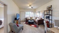 This single-story, 2-bedroom, 1-bathroom residence offers a practical and comfortable layout designed to maximize its compact footprint. The living room serves as the heart of the home, featuring soft carpeting, a ceiling fan with light fixture, and a large window that allows natural light to fill the space, creating a bright and welcoming atmosphere.

The kitchen is a standout feature, equipped with rich dark mahogany cabinetry, granite-style countertops, and a full suite of black appliances including a refrigerator, electric range, built-in microwave, and dishwasher. A mirrored backsplash adds depth to the space, while tile flooring and pendant lighting lend a polished, functional character.

The primary bedroom is a generously sized retreat, complete with plush carpeting, a ceiling fan, and wide windows fitted with blinds for light control and privacy. It is complemented by a spacious walk-in closet outfitted with multi-tier wire shelving, providing ample storage. The second bedroom also features carpeting, a ceiling fan, and a window for natural light.

The bathroom is finished with tile flooring, a dark wood vanity with a white sink, a wall-mounted mirror, and overhead lighting, offering a clean and practical design. Throughout the residence, neutral wall tones and consistent finishes create a cohesive and inviting ambiance.