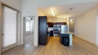 Located at 3603 Pavilion Palms Cir in Riverview, FL, this single-floor residence offers a well-designed open-concept layout with a clean, modern aesthetic throughout. The kitchen serves as the centerpiece of the living space, showcasing rich dark cabinetry, a white subway tile backsplash, granite countertops, and a full suite of stainless steel appliances including a refrigerator, electric range, and built-in microwave. A kitchen island with a granite surface provides additional prep and seating space, while track lighting and pendant fixtures create a warm, well-lit atmosphere. Light wood-style flooring flows seamlessly through the kitchen and main living area, which is bright and open with natural light streaming through multiple windows fitted with blinds and a ceiling fan overhead. The bedrooms feature plush carpeting, ceiling fans, and windows that allow for ample natural light. The primary bathroom is appointed with dark cabinetry, a granite vanity, large-format tile flooring, and a glass-enclosed shower, with direct access to a spacious walk-in closet with built-in shelving. A secondary bathroom mirrors the same refined finishes, offering a tub-shower combination and a granite-topped vanity. This residence combines functional design with quality finishes throughout.