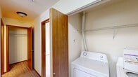 Located on the third floor at 16102 E Broadway Ave in Spokane Valley, WA, this one-bedroom, one-bathroom residence offers a well-organized layout designed for comfortable everyday living. The kitchen is equipped with warm wood-toned cabinetry, light countertops, a double-basin stainless steel sink, an electric range, a dishwasher, and a black refrigerator. Wood-style flooring runs throughout the kitchen, which opens toward the carpeted living area, creating a natural transition between spaces. A breakfast bar-style counter provides an additional surface for dining or meal prep. The bedroom is generously sized, featuring plush carpet, neutral walls, and a window that frames pleasant outdoor views of the surrounding Spokane Valley landscape, bringing in natural light. The full bathroom includes a wood-toned vanity with a single sink, wood-style flooring, and a clean, functional layout. A dedicated closet offers organized storage, and the hallway connects all rooms efficiently. A notable convenience feature is the in-unit laundry area, complete with a washer and dryer hookup and wire shelving above for additional storage. Warm-toned interior doors and trim add a cohesive, inviting character throughout the home.
