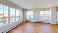 Located in the Macewan area of southwest Edmonton, this single-floor residence offers a thoughtfully designed layout encompassing two bedrooms, two full bathrooms, and three closets. Warm hardwood-style flooring runs consistently throughout the unit, complemented by neutral-toned walls and textured ceilings that create a clean, cohesive aesthetic.

The open-concept kitchen and living area serves as the heart of the home. The kitchen features light wood cabinetry, stainless steel appliances including a refrigerator, stove, and microwave, along with a peninsula with a light stone countertop, pendant lighting, and a double sink — ideal for both cooking and entertaining.

The spacious primary bedroom is filled with natural light from a large multi-pane window with outdoor views, and includes baseboard heating. The second bedroom similarly benefits from a generous window and bright, airy feel. Both rooms offer ample proportions and closet access.

The two bathrooms are finished with tub-shower combinations, clean white tile surrounds, and warm wood vanities with stone-look countertops. A connecting hallway ties all rooms together efficiently. The unit's layout maximizes functionality while maintaining a comfortable, welcoming atmosphere throughout.