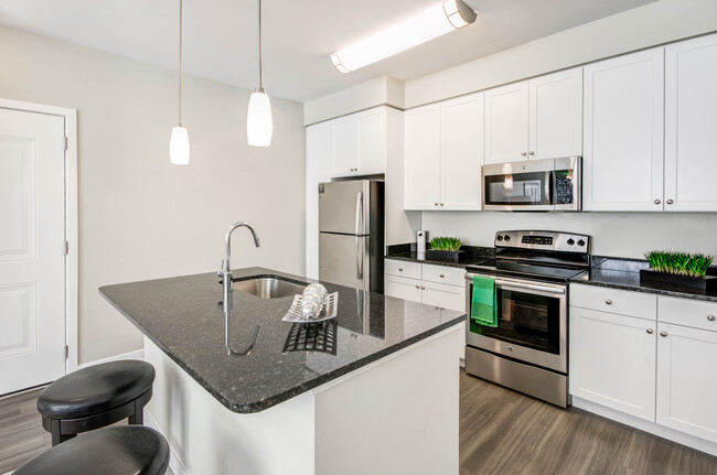 Kitchen with granite countertops, white shaker cabinetry, stainless steel appliances, kitchen island and hard surface flooring - Avalon Laurel