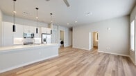 This well-appointed 2-bedroom, 2-bathroom single-story residence offers a thoughtfully designed open-concept layout that maximizes both functionality and comfort. The combined kitchen and living area serves as the heart of the home, showcasing light wood-style flooring, recessed lighting, and a ceiling fan. The kitchen is outfitted with crisp white shaker cabinetry, a subway tile backsplash, stainless steel appliances including a refrigerator with ice maker, a stainless steel sink, and a large island with light quartz countertops illuminated by sleek pendant lighting. The living area benefits from multiple windows and a glass door that floods the space with natural light. A well-connected hallway leads to both bedrooms, each featuring plush carpet flooring, ceiling fans, and generously sized windows. Three closets provide ample storage throughout. The bathrooms are finished with clean, modern fixtures, with one featuring a full tub-shower combination enclosed by classic white subway tile and a built-in niche. A dedicated laundry room houses a full-size front-loading washer and dryer. The overall aesthetic is clean, contemporary, and move-in ready.