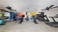 This 460 square foot fitness center, located in Las Vegas, offers a comprehensive workout space within a compact footprint. The facility features a variety of cardio and strength training equipment, including treadmills, ellipticals, stationary bikes, and weight machines. The room is adorned with motivational wall graphics, creating an energizing atmosphere for exercisers.

The space boasts modern amenities such as ceiling fans for air circulation, recessed lighting, and a wall-mounted TV for entertainment. Large exercise balls in vibrant colors add a pop of visual interest and versatility to workout routines. A rack of free weights and additional strength training equipment line the walls, maximizing the use of available space.

The fitness center's layout is well-organized, with equipment strategically placed to allow for easy movement and access. Light-colored wood-look flooring enhances the bright, clean aesthetic of the room. Glass doors provide natural light and offer a view to the outside, creating a sense of openness in the compact space. A bulletin board near the entrance allows for posting of schedules or announcements, adding to the functional design of this efficient fitness facility.