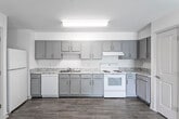 This single-floor residence offers a thoughtfully designed layout with a clean, modern aesthetic throughout. The open-concept living and dining area flows seamlessly into a generously sized kitchen, creating an inviting communal space. Durable wood-look flooring runs through the main living areas, adding warmth and easy maintenance underfoot.

The kitchen is well-equipped with gray shaker-style cabinetry, granite-patterned countertops, a double-basin sink, and white appliances including a refrigerator, dishwasher, and range with overhead ventilation. Ample upper and lower cabinet storage makes this a highly functional cooking space.

The bedrooms feature plush carpeting and crisp white walls, fostering a calm and comfortable atmosphere. Multiple bedrooms include generous closet space with bifold doors, while at least one bedroom benefits from a large window offering outdoor views and abundant natural light.

The bathrooms maintain a cohesive design language with gray vanity cabinetry, granite-style countertops, full-size tub-shower combinations with white tile surrounds, and wood-look flooring. The overall color palette of soft whites and grays creates a bright, neutral ambiance throughout the entire residence, lending itself well to a variety of interior styles.