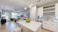 Located on International Drive in Orlando, Florida, this single-floor, 2-bedroom, 2-bathroom residence offers a thoughtfully designed layout with modern finishes throughout. Light wood-style flooring flows seamlessly across the entire space, creating a cohesive and airy feel.

The open-concept living and dining area is anchored by large windows that invite abundant natural light and provide outdoor views. A ceiling fan adds comfort, while a glass-paned door opens to a balcony, extending the living space outdoors.

The kitchen is outfitted with white shaker cabinetry, quartz countertops, stainless steel appliances, and a soft grey subway tile backsplash with under-cabinet lighting — a clean, contemporary look ideal for everyday cooking and entertaining.

Both bedrooms are generously sized and feature ceiling fans, large windows with natural light, and direct access to their respective bathrooms. The primary bedroom is spacious, with a walk-in closet featuring multi-level wire shelving. A second closet with wire rack storage serves the additional bedroom.

The bathrooms are sleek and modern, featuring white vanities with quartz countertops and large mirrors. A dedicated laundry room houses a full-size Whirlpool washer and dryer with additional overhead shelving, completing this well-equipped and functional residence.