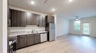 Located in Middleburg, Florida, this single-story residence offers a thoughtfully designed layout with 1 bedroom, 2 bathrooms, a kitchen, laundry room, and hallway. Light wood-look flooring flows throughout the open-concept living and kitchen areas, creating a bright and cohesive feel. The kitchen is well-equipped with dark wood cabinetry, granite-style countertops, a tile backsplash, and a full suite of stainless steel appliances including a refrigerator, dishwasher, microwave, and range. A ceiling fan overhead enhances comfort in the living area, which benefits from natural light through a glass-paned exterior door. The primary bedroom features plush carpeting, a ceiling fan, and a window with outdoor views of greenery. The bathrooms are finished with matching dark wood vanities, granite-style countertops, and large mirrors. One bathroom includes a walk-in shower, while the other features a full tub-shower combination with tiled surround and built-in shelving. The dedicated laundry room houses a full-size washer and dryer with overhead wire shelving for additional storage. Clean neutral walls and consistent finishes throughout give the space a modern, move-in-ready appeal.