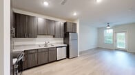 Located in Middleburg, Florida, this single-story residence offers a thoughtfully designed layout with 1 bedroom, 2 bathrooms, a kitchen, laundry room, and hallway. Light wood-look flooring flows throughout the open-concept living and kitchen areas, creating a bright and cohesive feel. The kitchen is well-equipped with dark wood cabinetry, granite-style countertops, a tile backsplash, and a full suite of stainless steel appliances including a refrigerator, dishwasher, microwave, and range. A ceiling fan overhead enhances comfort in the living area, which benefits from natural light through a glass-paned exterior door. The primary bedroom features plush carpeting, a ceiling fan, and a window with outdoor views of greenery. The bathrooms are finished with matching dark wood vanities, granite-style countertops, and large mirrors. One bathroom includes a walk-in shower, while the other features a full tub-shower combination with tiled surround and built-in shelving. The dedicated laundry room houses a full-size washer and dryer with overhead wire shelving for additional storage. Clean neutral walls and consistent finishes throughout give the space a modern, move-in-ready appeal.