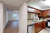 Located at 6915 Main St in Miami Lakes, FL, this well-appointed 2-bedroom, 2-bathroom residence offers a thoughtfully designed single-floor layout. The combined living and dining area is bright and open, featuring hardwood-style flooring, crown molding, track lighting, and natural light streaming through large windows and sliding glass doors that lead to a private balcony. The kitchen is efficiently designed with rich wood cabinetry, granite-style countertops, a tile backsplash, and a full suite of stainless steel appliances including a refrigerator, electric range, built-in microwave, and dishwasher. The generously sized primary bedroom features plush carpeting, a ceiling fan, and sliding glass doors opening directly to the balcony, offering outdoor access and natural light. The second bedroom is equally comfortable, with carpet flooring, a ceiling fan, and a bright window. Both bathrooms are clean and functional, each featuring a single vanity with white cabinetry, a mirror, and wood-style flooring; one includes a tub/shower combination. Additional highlights include five closets for abundant storage, a dedicated laundry area, a utility room, and two hallways connecting the layout seamlessly throughout.