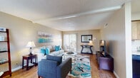 Located at 6200 N Oracle Rd in Tucson, Arizona, this single-floor residence offers a well-organized and comfortable layout designed for everyday living. The spacious living room serves as the heart of the home, featuring warm hardwood-style flooring, vaulted ceilings with exposed beam detailing, and a textured ceiling finish. Natural light streams in through sliding glass doors that open to an outdoor balcony, creating an inviting and airy atmosphere. The kitchen is outfitted with rustic wood-grain cabinetry, light-toned countertops, a double-basin sink, and black appliances including a refrigerator, range, and dishwasher. Adjacent to the kitchen, a dedicated dining nook provides a cozy space for meals, brightened by a large window with vertical blinds that frame outdoor views. The bedroom is generously sized with plush carpeting, multiple closets offering ample storage, and windows that allow in soft natural light. A dedicated laundry area with stacked washer and dryer units is conveniently accessible from the bedroom. The full bathroom features wood-style flooring, a shower/tub combination, and a vanity with storage. Throughout the home, neutral warm tones create a cohesive and welcoming ambiance.