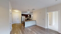 Located at 527 Old Bridge Turnpike in East Brunswick, NJ, this well-appointed two-bedroom, two-bathroom residence offers a thoughtfully designed single-floor layout. The open-concept kitchen and living area serves as the heart of the home, featuring dark espresso cabinetry, granite countertops, a kitchen island with pendant lighting, and a full suite of stainless steel appliances including a refrigerator, electric range, microwave, and dishwasher. Hardwood-style flooring runs throughout the main living areas, adding warmth and continuity to the space. The living room is bright and airy, anchored by a sliding glass door that opens to a private balcony with outdoor views of lush greenery. The spacious primary bedroom offers generous closet space and plush carpeting, while the second bedroom benefits from natural light through a large window and matching carpet flooring. Both bathrooms are well-finished, with one featuring a glass-enclosed walk-in shower with white subway tile and granite vanity countertops. A hallway connects all areas of the residence seamlessly. Neutral tones throughout create a clean, modern aesthetic that is both functional and inviting.