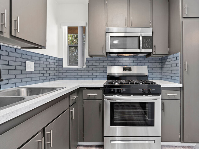 Blue tiled kitchen with stainless steel fridge, oven, and microwave. - Olive View Gardens