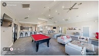 This expansive 1,930 square foot community space in Raleigh, NC, showcases a blend of modern design and multifunctional areas. The interior boasts vaulted ceilings, creating an airy and spacious atmosphere. The main living area features a sleek fireplace, large-screen TV, and comfortable seating, perfect for gatherings. A striking red egg chair adds a pop of color to the neutral palette.

The space incorporates several work areas, including an office with glass partitions, offering transparency while maintaining separate zones. Red chairs provide vibrant accents throughout, contrasting with the crisp white walls and grey carpeting. A kitchen area with a breakfast bar adds convenience, while a fitness center, accessible through glass doors, promotes an active lifestyle.

For entertainment, the space includes a billiards room with a red pool table, continuing the color theme. The overall design emphasizes openness, with seamless transitions between areas. Ample recessed lighting and large windows ensure the space is well-lit. Artwork adorns the walls, adding visual interest and personality to the contemporary setting. This versatile community space effectively balances work, leisure, and social needs in a cohesive, modern environment.