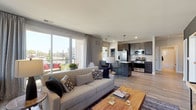 This single-floor residence is designed with a contemporary aesthetic, combining functionality and style across its thoughtfully arranged layout. The open-concept living and kitchen area forms the heart of the home, where light wood-style flooring flows seamlessly underfoot. Large sliding glass doors in the living room flood the space with natural light and provide direct access to a private balcony with exterior views, creating a strong indoor-outdoor connection.

The kitchen is well-appointed with dark espresso cabinetry, a full suite of stainless steel appliances including a gas range, microwave, and French door refrigerator, and a granite-topped island with an integrated sink and bar seating illuminated by pendant lighting. A built-in pantry adds additional storage convenience.

The living area features a striking dark accent wall with floating wood shelves, offering a bold contrast to the neutral tones elsewhere. Two bedrooms provide comfortable retreats, each with natural light from windows and light wood flooring. The primary bathroom includes a glass-enclosed walk-in shower with tile detailing and a dark-cabineted vanity, while the secondary bathroom features a soaking tub with tiled surround and a matching vanity, completing this well-designed residence.