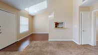 Located at 5020 Fairbanks Dr in El Paso, Texas, this single-story home offers a thoughtfully designed layout with a mix of warm finishes and functional spaces throughout. The living area immediately impresses with its vaulted ceiling, a skylight that floods the room with natural light, and a combination of hardwood-style flooring and plush carpeting. A pass-through shelf connects the living space to the kitchen, enhancing the open feel of the common areas. The galley-style kitchen is well-appointed with warm oak cabinetry extending to the upper walls for generous storage, light-toned countertops, a double-basin sink, and white appliances including a full-size refrigerator. Hardwood-style flooring runs throughout the kitchen, adding continuity to the space. The bedrooms are carpeted and bathed in natural light from well-placed windows with blinds, offering comfortable and versatile spaces. High ceilings continue into the bedroom areas, reinforcing the sense of openness. A hallway with access to a closet connects the rooms seamlessly. The home's neutral warm-beige palette and clean white trim throughout lend a cohesive, inviting ambiance well-suited for a variety of décor styles.