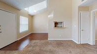 Located at 5020 Fairbanks Dr in El Paso, Texas, this single-story home offers a thoughtfully designed layout with a mix of warm finishes and functional spaces throughout. The living area immediately impresses with its vaulted ceiling, a skylight that floods the room with natural light, and a combination of hardwood-style flooring and plush carpeting. A pass-through shelf connects the living space to the kitchen, enhancing the open feel of the common areas. The galley-style kitchen is well-appointed with warm oak cabinetry extending to the upper walls for generous storage, light-toned countertops, a double-basin sink, and white appliances including a full-size refrigerator. Hardwood-style flooring runs throughout the kitchen, adding continuity to the space. The bedrooms are carpeted and bathed in natural light from well-placed windows with blinds, offering comfortable and versatile spaces. High ceilings continue into the bedroom areas, reinforcing the sense of openness. A hallway with access to a closet connects the rooms seamlessly. The home's neutral warm-beige palette and clean white trim throughout lend a cohesive, inviting ambiance well-suited for a variety of décor styles.