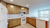 This thoughtfully designed 1-bedroom, 1-bathroom residence at 1593 Hartwell Dr in Carver, MN offers an efficient and comfortable single-floor layout. The combined kitchen and living area forms the heart of the unit, highlighted by warm medium-toned wood cabinetry, light countertops, and a peninsula that creates a natural division between cooking and living spaces. The kitchen is equipped with a full suite of white appliances including a refrigerator, electric range, dishwasher, and microwave, all set atop light wood-style flooring that extends throughout the main living area. Recessed lighting illuminates the space cleanly and evenly. The bedroom offers a cozy carpeted floor, a window with exterior views that brings in natural light, and direct access to a dedicated walk-in closet with built-in shelving and hanging rods, plus an additional closet for extra storage. The bathroom is finished with stone-look tile flooring, a single-sink vanity with a light wood base, and includes accessibility-minded features such as stainless steel grab bars. Additional practical spaces include a dedicated laundry area and a utility room. The overall aesthetic is clean, neutral, and move-in ready.