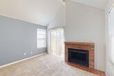 Located at 9937 E Louisiana Dr in Aurora, CO, this one-bedroom, one-bathroom home offers a thoughtfully laid-out single-floor plan that maximizes every square foot. The living room immediately impresses with dramatic vaulted ceilings accented by exposed beams, creating an airy, open atmosphere. A standout brick fireplace with a tile hearth anchors the space, complemented by a sliding glass door and adjacent window that invite abundant natural light. The entry features classic brick-patterned tile flooring that transitions seamlessly into plush carpeting throughout the main living areas. The kitchen is equipped with warm-toned wood cabinetry, a granite-topped peninsula that opens to the living area, a range, and a refrigerator, all beneath a skylight that brightens the space. The bedroom is generously sized, featuring a ceiling fan, two windows for cross-ventilation, and access to a dedicated closet. A second carpeted room with a ceiling fan and bold accent wall offers additional flexible space. The bathroom includes a full tub-shower combination with clean white tile surrounds. Throughout the home, a cohesive color palette of soft grays and whites lends a calm, neutral ambiance well-suited for comfortable everyday living.