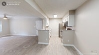 This single-floor, 2-bedroom, 2-bathroom residence offers a functional and thoughtfully updated layout. The kitchen is a standout feature, boasting white shaker cabinetry with modern hardware, granite countertops, a subway tile backsplash, and stainless steel appliances including a refrigerator, range, microwave, and dishwasher. Light wood-style flooring runs throughout the main living areas, lending a clean, contemporary aesthetic. A peninsula with additional counter space connects the kitchen to the open living area, which is bright and airy thanks to a large window and glass-panel door that invite natural light. A ceiling fan adds comfort to the living room. Both bedrooms are carpeted and feature ceiling fans, with the primary bedroom offering a generously sized en-suite bathroom complete with a granite-topped vanity, framed mirror, and access to a walk-in closet with built-in shelving. The second bathroom mirrors the refined finishes found throughout the home. Additional highlights include a dedicated utility room, two closets, and a neutral color palette that creates a cohesive, move-in-ready atmosphere throughout the entire residence.
