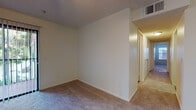 Located at 5800 Auvers Blvd in Orlando, Florida, this single-floor residential unit offers a practical and comfortable layout designed for everyday living. The living area features plush carpeting and a sliding glass door dressed with vertical blinds, inviting natural light and providing a view of the lush greenery outside. A pass-through window connects the living space to the kitchen, enhancing the open feel between the two areas. The kitchen is equipped with wood-trimmed cabinetry, a coil-top electric range with overhead ventilation, a single-basin sink, and ample counter space — all finished with a classic, functional aesthetic. Hardwood flooring in the kitchen and bathrooms adds warmth and easy maintenance to key areas of the home. The bedrooms are generously proportioned, each featuring soft carpeting, neutral walls, textured ceilings, and access to closet space. Natural light filters in through windows with blinds. Both bathrooms follow a consistent design, featuring a tub-shower combination with tiled surrounds, a vanity with under-sink cabinetry, a large mirror, and hardwood flooring. Throughout the unit, a clean, neutral color palette creates a welcoming and move-in-ready atmosphere.