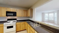 Unit 317D at Fox Hill Run is a single-floor residence designed with a practical, comfortable layout. The kitchen is well-equipped with ample light oak cabinetry, dark speckled countertops, a gas range, built-in microwave, refrigerator, and a stainless steel sink. A pass-through opening connects the kitchen to the adjacent living area, enhancing the sense of openness between spaces.

The living area is generously proportioned, featuring neutral wall-to-wall carpeting and crisp white walls that create a bright, airy atmosphere. Multiple windows allow natural light to filter throughout, and a sliding glass door provides direct access to a private balcony, extending the living space outdoors.

The bedrooms are carpeted and well-sized, each with windows that bring in natural light and offer views of the surrounding neighborhood. The rooms offer versatile layouts suitable for a variety of furniture arrangements.

Two full bathrooms serve the unit. One features a tiled tub-shower combination with sliding glass doors, a light oak vanity, and tile flooring. The second bathroom includes tile wainscoting, a matching oak vanity, and tile floors, providing a clean, functional design throughout. The overall ambiance of the unit is neutral, move-in ready, and well-suited for comfortable everyday living.