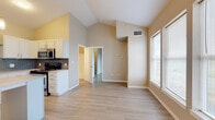 Located at 19768 Pikes Peak Ave in Parker, Colorado, this single-floor residence offers a well-designed open-concept layout enhanced by striking vaulted ceilings that lend a sense of generous vertical space throughout the main living area. Light wood-tone flooring runs consistently across the unit, contributing to a clean, cohesive aesthetic.

The living area is bright and airy, benefiting from large windows fitted with blinds that invite substantial natural light while maintaining privacy. Neutral beige and warm gray tones on the walls complement the overall modern palette.

The kitchen is a functional highlight of the space, featuring white shaker-style cabinetry, light quartz countertops, and a bold blue-gray subway tile backsplash. Stainless steel appliances include a gas range, built-in microwave, refrigerator, and dishwasher. A peninsula island provides additional counter space and casual seating potential.

A dedicated laundry area accommodates a stacked washer and dryer unit, offering in-unit convenience. The bathroom includes a full soaking tub and shower combination with clean white tile surround and chrome fixtures.

Overall, the space presents a modern, well-appointed interior with practical amenities and an open, light-filled atmosphere suited to comfortable everyday living.