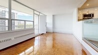 Located at 45 Balliol St in Toronto's desirable Davisville Village neighbourhood, this two-bedroom unit offers a well-considered layout across a single floor. Gleaming herringbone parquet hardwood floors flow throughout the living areas and both bedrooms, lending the space a warm, classic character. The open-concept kitchen and living room area features a raised platform with a large corner window that fills the space with natural light and frames sweeping city views. The kitchen is outfitted with stainless steel appliances, including a range, built-in microwave, and dishwasher, complemented by white cabinetry, stone countertops, and a contemporary mosaic tile backsplash. The primary bedroom is generously sized and includes double closets, while the second bedroom also benefits from ample closet storage and direct city views through large windows. Both bedrooms carry the same warm parquet flooring seen throughout the unit. A tiled entryway hallway provides a clean transition into the main living spaces. Crisp white walls and clean lines throughout contribute to a bright, airy ambiance. The unit is ideally situated near transit, parks, and the amenities of Midtown Toronto.