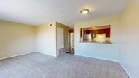 Located on Jewella Avenue in Shreveport, Louisiana, this single-floor, one-bedroom, one-bathroom unit offers a functional and comfortable layout. The open living room is finished with plush wall-to-wall carpeting and warm neutral-toned walls, creating a welcoming atmosphere. A large window allows natural light to fill the space and provides a view of the outdoors. The kitchen is positioned adjacent to the living area and features a pass-through bar counter, rich dark wood cabinetry, a stainless steel refrigerator, a white electric range, and under-cabinet lighting — making it both practical and visually connected to the main living space. Hardwood-style flooring runs through the kitchen and entry areas, providing a clean contrast to the carpeted rooms. The bedroom is generously sized, featuring carpet flooring, a ceiling fan with light fixture, a window with blinds, and direct access to a closet. An additional closet provides extra storage. The bathroom is appointed with wood-toned cabinetry, a light countertop, hardwood-style flooring, a tiled shower-tub combination, and a toilet. Textured ceilings are consistent throughout the unit, and central HVAC vents are present in each room, ensuring year-round comfort.