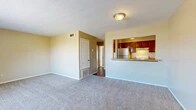 Located on Jewella Avenue in Shreveport, Louisiana, this single-floor, one-bedroom, one-bathroom unit offers a functional and comfortable layout. The open living room is finished with plush wall-to-wall carpeting and warm neutral-toned walls, creating a welcoming atmosphere. A large window allows natural light to fill the space and provides a view of the outdoors. The kitchen is positioned adjacent to the living area and features a pass-through bar counter, rich dark wood cabinetry, a stainless steel refrigerator, a white electric range, and under-cabinet lighting — making it both practical and visually connected to the main living space. Hardwood-style flooring runs through the kitchen and entry areas, providing a clean contrast to the carpeted rooms. The bedroom is generously sized, featuring carpet flooring, a ceiling fan with light fixture, a window with blinds, and direct access to a closet. An additional closet provides extra storage. The bathroom is appointed with wood-toned cabinetry, a light countertop, hardwood-style flooring, a tiled shower-tub combination, and a toilet. Textured ceilings are consistent throughout the unit, and central HVAC vents are present in each room, ensuring year-round comfort.