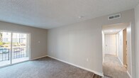 This single-floor, 3-bedroom, 1-bathroom residence offers a practical and well-organized layout designed for comfortable everyday living. Throughout the home, neutral beige tones, white trim, and textured ceilings create a consistent and clean aesthetic. Plush carpeting covers the bedrooms and living areas, while wood-look flooring runs through the kitchen and entry hallway.

The living room is a generously sized space featuring a sliding glass door that opens to an outdoor balcony, filling the room with natural light and providing pleasant exterior views. The kitchen is equipped with white shaker-style cabinetry, light countertops, a double basin stainless steel sink, a dishwasher, and a full-size refrigerator, offering ample storage and functional workspace.

Each of the three bedrooms features soft carpeting and neutral walls. The primary bedroom is a well-proportioned room with good natural light. One bedroom includes a closet with sliding panel doors and a hanging rod, providing practical storage. The full bathroom features a white tub and shower surround with built-in shelving and brushed nickel fixtures. Two hallways connect the rooms efficiently, and two closets offer additional storage throughout the home.