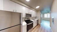 Located at 3158 SW 12th Ave in Portland's vibrant SW neighborhood, this single-floor unit offers a thoughtfully designed and modern living space. The kitchen is a standout feature, showcasing sleek white cabinetry extending floor to ceiling, a full suite of stainless steel appliances including a refrigerator, electric range, over-the-range microwave, and dishwasher, along with clean white countertops and light wood-style flooring that flows throughout the unit. The galley-style layout maximizes efficiency while maintaining a bright, contemporary feel. The living area is open and versatile, bathed in a neutral palette with clean white walls that provide a blank canvas for personalization. The bedroom features a window with outdoor views of the surrounding neighborhood, a ceiling fan with integrated lighting, and a wall-mounted mini-split system for individualized climate control year-round. The full bathroom is well-appointed with a white vanity, a large mirror, and a tiled shower-tub combination, offering both style and functionality. Light wood-style flooring and neutral warm-toned walls are consistent throughout, lending the space a cohesive, modern aesthetic. The unit is ideal for those seeking a clean, updated living environment in Portland, Oregon.