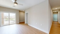 This well-appointed single-floor residence offers a thoughtfully designed layout that balances open living spaces with comfortable private areas. The kitchen serves as a central highlight, showcasing crisp white shaker cabinetry, quartz countertops, a large island with an undermount stainless steel sink and a professional-style pull-down faucet, and a full suite of stainless steel appliances including a refrigerator, electric range, over-the-range microwave, and dishwasher. Elegant pendant lighting illuminates the island, adding a modern touch to the space. Light wood-tone flooring extends throughout the main living and kitchen areas, lending warmth and continuity. The bedrooms are finished with plush neutral carpeting and feature ceiling fans, generous windows with blinds that invite natural light and outdoor views, and ample closet space including double-door closets. A dedicated laundry area houses a full-size Whirlpool washer and dryer with built-in shelving above. The bathroom is outfitted with a soaking tub and shower combination featuring tiled surround with integrated shelving. Neutral beige tones throughout the walls, clean white trim, and recessed lighting create a bright, cohesive, and move-in-ready atmosphere across the entire residence.