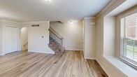Located at 13100 Woodridge Cir in Plymouth, Michigan, this three-bedroom, four-bathroom home spans three well-appointed floors. The main level opens to a bright living room with wood-look luxury vinyl flooring, crown molding, and a large window that fills the space with natural light. The adjacent kitchen is thoughtfully designed with white shaker cabinetry, granite countertops, a tile backsplash, stainless steel appliances, and matching wood-look flooring that ties the entertaining area together seamlessly. A staircase with decorative iron balusters connects the floors with an elegant touch. The upper floors feature carpeted bedrooms with vaulted ceilings that lend an airy, open feel. The generously sized primary bedroom includes a walk-in closet with built-in shelving and an en-suite bathroom boasting a dual-sink granite vanity and a large walk-in shower clad in marble-style tile with a built-in bench. Additional bedrooms are well-proportioned with carpet flooring and access to natural light. The lower level provides a spacious carpeted bedroom or flex room with a window, a utility area, and additional bathroom access. Throughout the home, neutral tones and clean finishes create a cohesive, move-in-ready aesthetic.
