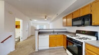 This three-floor townhome at 2252 Par Lane in Willoughby Hills, Ohio offers a well-organized layout across its levels. The ground floor houses an attached garage with an automatic opener, providing convenient and secure parking. The main living level features an open-concept design where the kitchen flows seamlessly into the dining and living areas. The kitchen is equipped with warm honey-toned cabinetry, a gas range, built-in microwave, dishwasher, and a black refrigerator, complemented by light wood-style flooring and a bright window overlooking the outdoors. The spacious living room features plush carpeting, a ceiling fan, and a staircase that connects the floors. The upper level hosts two bedrooms, including a generously sized primary bedroom with plush carpet, a mirrored sliding-door closet, a ceiling fan, and a window with outdoor views. The second bedroom is equally well-proportioned with carpeting and natural light. Three bathrooms are distributed throughout the home, featuring wood-toned vanities and wood-style vinyl flooring. Additional highlights include a balcony, dedicated laundry room, utility room, hallway, and multiple closets, rounding out a functional and comfortable living space.