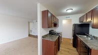 This single-floor residence at 783 Huntington Dr in Aurora, IL offers a well-organized layout with functional living spaces throughout. The galley-style kitchen is a standout feature, lined on both sides with rich, dark-stained wood cabinetry that extends to the upper walls, providing ample storage. Granite-style countertops run along both sides, complemented by black appliances including a range, refrigerator, and dishwasher, all set atop warm wood-style flooring that carries through the kitchen and adjacent areas.

The kitchen opens toward the living area, which transitions to plush carpeting and is bathed in natural light through large windows dressed with vertical blinds. A ceiling fan adds to the comfort of this bright, open space. The layout flows efficiently, connecting the main living zone to a hallway that leads to the additional rooms.

The bedroom is a quiet, carpeted space featuring a window with vertical blinds that allows natural light to filter in, along with dual closet doors offering generous storage. The bathroom is cleanly finished with a full tub-and-shower combination, a white vanity with a solid countertop, wood-style flooring, and simple, modern fixtures. Overall, the space presents a clean, functional, and comfortable living environment.