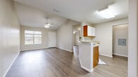 This well-organized single-floor unit offers a functional and comfortable layout across its 1 bedroom and 1 bathroom. The open-concept living and kitchen area serves as the heart of the home, featuring vaulted ceilings that lend a sense of spaciousness and a ceiling fan for added comfort. Wood-style flooring runs consistently throughout the entire unit, providing a clean, cohesive look. A large window in the living area allows natural light to fill the space, with views of the surrounding greenery. The kitchen is designed as a galley-style layout with a peninsula countertop that opens to the living area. Warm wood-toned cabinetry, white appliances including a refrigerator, electric range, and dishwasher, and ample upper cabinet storage make this kitchen highly functional. The bedroom is a comfortable size, featuring a ceiling fan, natural light from a window, and direct access to a walk-in closet outfitted with built-in shelving and dual clothing rods. The full bathroom includes a vanity with storage drawers, a toilet, and a shower-tub combination. A dedicated hallway connects all rooms, and an electrical panel is conveniently accessible near the kitchen. The neutral color palette throughout gives the space a bright, clean, and move-in-ready feel.