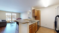 Located at 124 Ferry St in Troy, NY, this single-floor, 3-bedroom, 1-bathroom unit offers a practical and comfortable layout. The combined kitchen and living room serves as the heart of the space, featuring warm wood-toned cabinetry, a peninsula with a double sink and bar seating, a dishwasher, and a full-size refrigerator. The kitchen flows seamlessly into the living area, which is finished with hardwood-style flooring and bright windows that bring in generous natural light and views of the surrounding neighborhood. The three bedrooms are carpeted for comfort, each with neutral walls and windows allowing ample daylight. The primary bedroom offers a spacious layout with room for a bed and workspace. The additional bedrooms are well-proportioned and versatile, suitable for sleeping or office use. A shared hallway connects the living spaces to the bathroom, which features tile flooring, a vanity, and clean, minimal finishes. A dedicated closet provides added storage. The overall design is clean and functional, with a neutral color palette throughout that lends itself to easy personalization. The unit also includes a hallway connecting all rooms efficiently.